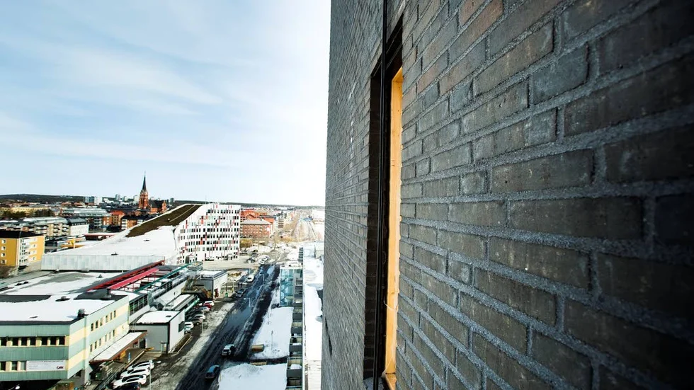 Det svartbrända teglet muras för hand vid det 15 våningar höga husets alla hörn.