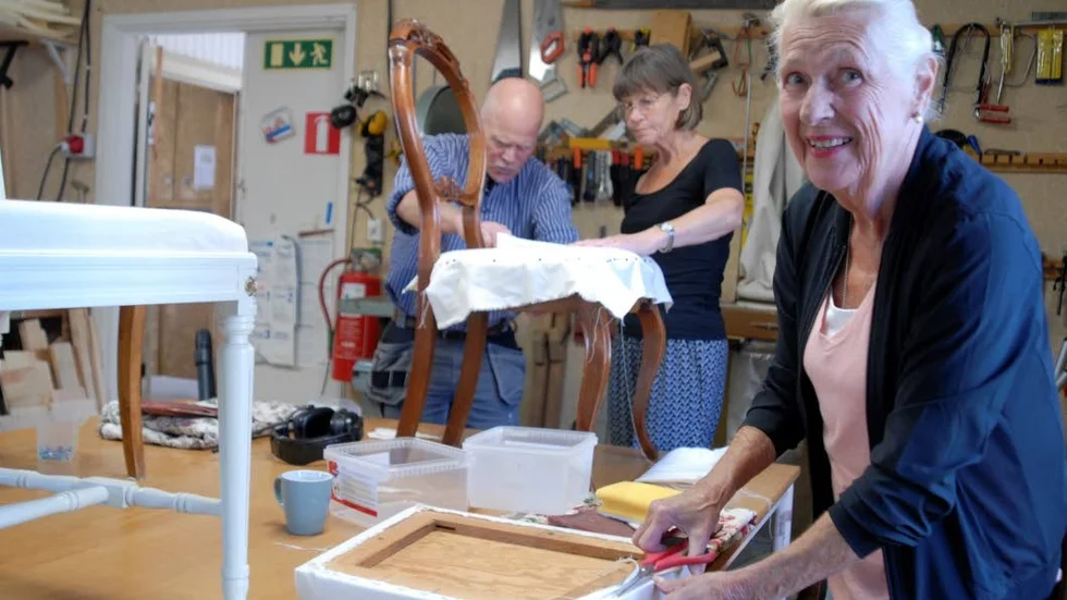 Gunilla Eklenius, 78 fyllda, stoppar och klär om stolsitsar under en kurs i möbelrenovering. I bakgrunden läraren Ulf Sandqvist och Kerstin Larsson, en av de andra kursdeltagarna.