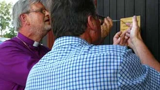 Biskop Martin Lind välsignade på torsdagen den nya maskinhallen i Fornåsa och skruvade tillsammans med Kyrkans jordbruksförvaltare Örjan Carlsson upp en gyllene skylt på porten. Bild: HELENE FOLKESSON