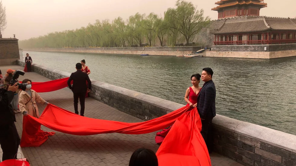 Nygifta par poserar vid Förbjudna staden i Peking. Arkivbild.