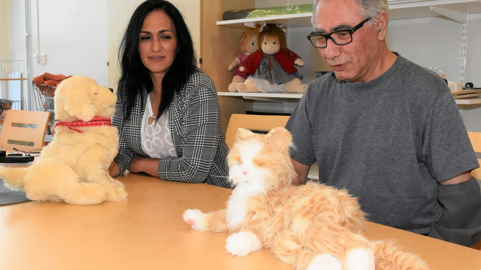 Zahra Gohari och Bijan Mohammadi, personal på Kronans äldreboende, visar upp robothunden och -katten.
