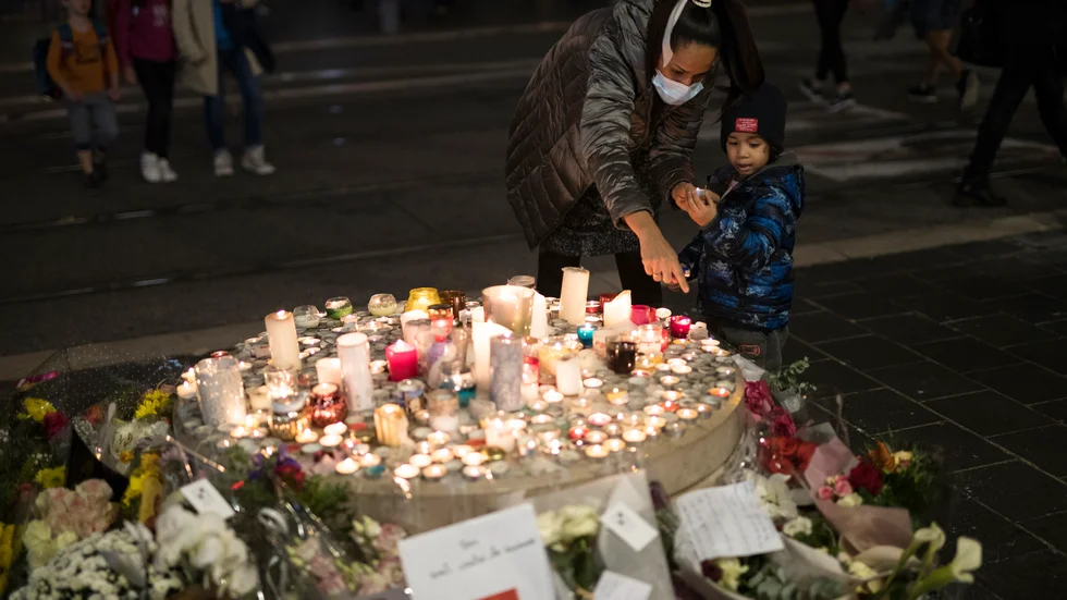 En familj tänder ljus utanför Notre Dame i Nice.