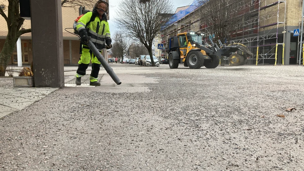 Nu är sandupptagningen igång. Här syns Kjell Jonsson på kommunens gatuavdelning som använder en lövblås för att blåsa ut gruset så att de större maskinerna kommer åt.