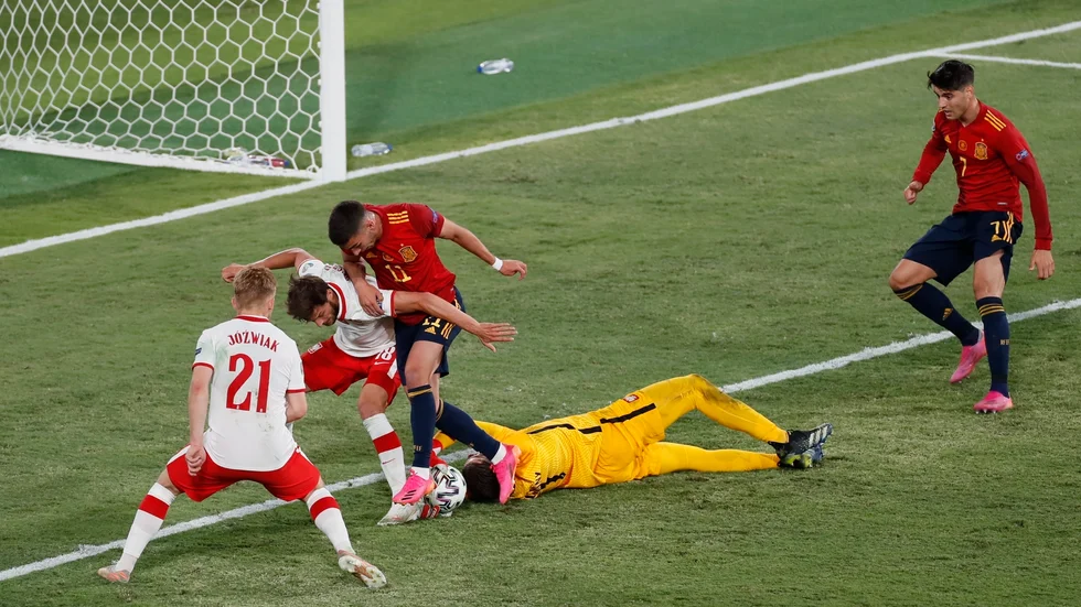Polens målvakt Wojciech Szczesny räddar i en rörig situation framför spanska anfallare.