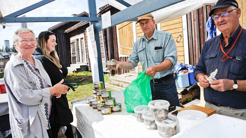 Gerd Tjärnström som var på skördemarknaden med sitt barnbarn My Tjärnström, köpte strömming av Sören Karlsson, till höger. Till sin hjälp hade han Carl-Gustav Brännström.