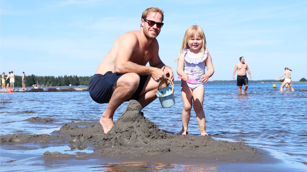 Oscar Lindberg och dottern Luna bygger sandslott ute i vattnet.