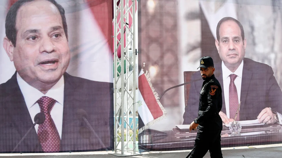 En polis från Hamas patrullerar framför ett porträtt på Egyptens president Abd al-Fattah al-Sisi i maj 2021, i samband med att Egyptens underrättelsechef besökte Gaza.
