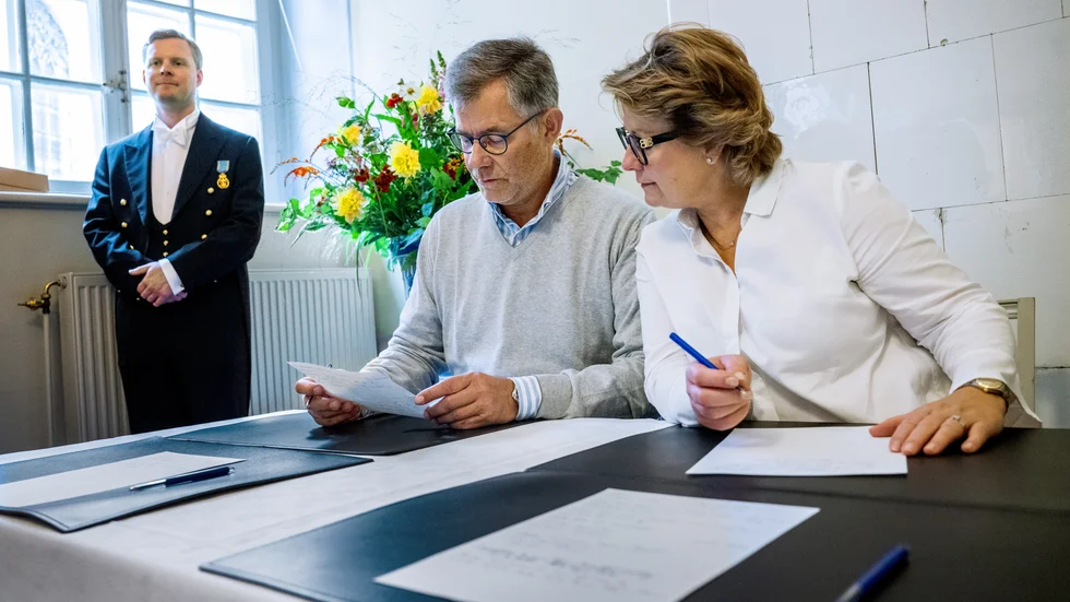 Peter och Hanna Malmström från Stockholm skriver gratulationer till kungen under överinseende av hovlakej Valter Nordkvist.