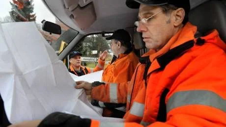 Per Fredén från Va-verket studerar begrundande ritningar över Överums vattenledningsnät. Bredvid sitter Göran Fridell och utanför bilen står Roy Nilsson.