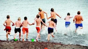 Bad i Brevik. Den inofficiella badplatsen i Brevik är öppen igen och badandet är i full gång och ett gäng fritidselever från Breviksskolan kastar sig glatt i vattnet. Tyvärr har även nya hål med blålera uppstått och leker barnen i den är det risk för att badplatsen blir farlig igen. Foto: Anders Steiner