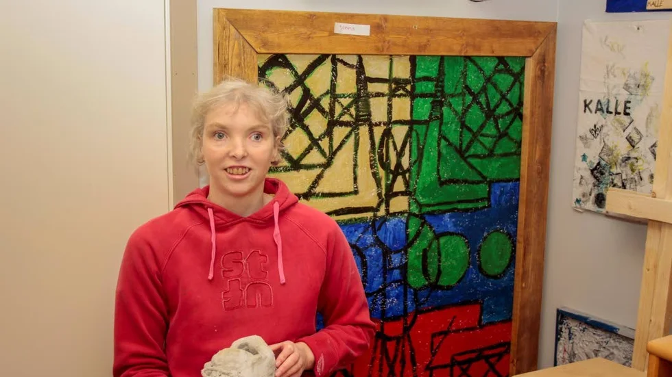 Janna visar upp en av sina målningar samt ett annat konstverk.