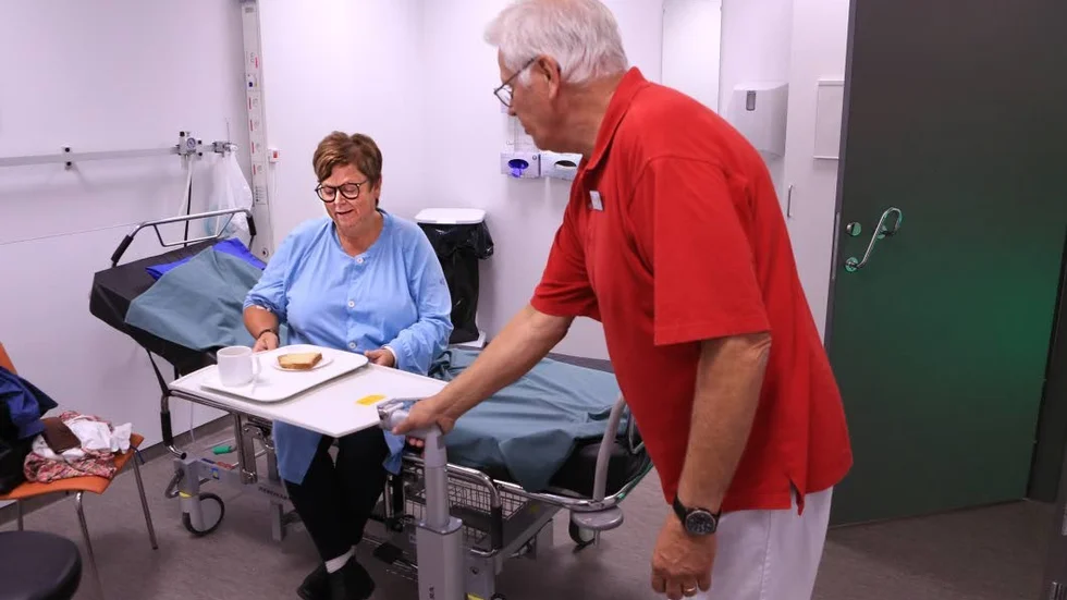 Lars-Olov Johansson är en av sexton Röda korset-volontärer som turas om att hjälpa till på akuten. Här serverar han fika till patienten Katarina Klingstedt.