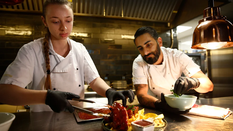 Elin Zwosta Reifner och Amer Raza lägger noggrant upp maten innan servering.