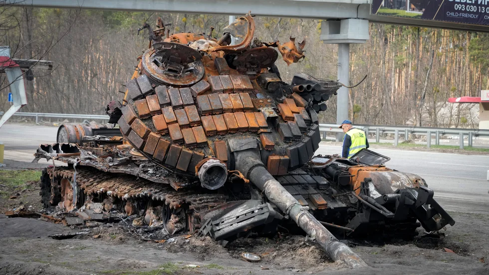 En ukrainsk funktionär undersöker en utbränd rysk stridsvagn vid en motorväg utanför Kiev i början av april.