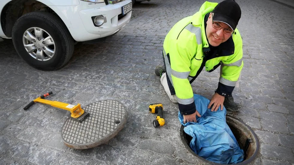 Anders Ekström lyfter på locket till rören under gatan. Där sitter en spjutfälla monterad.