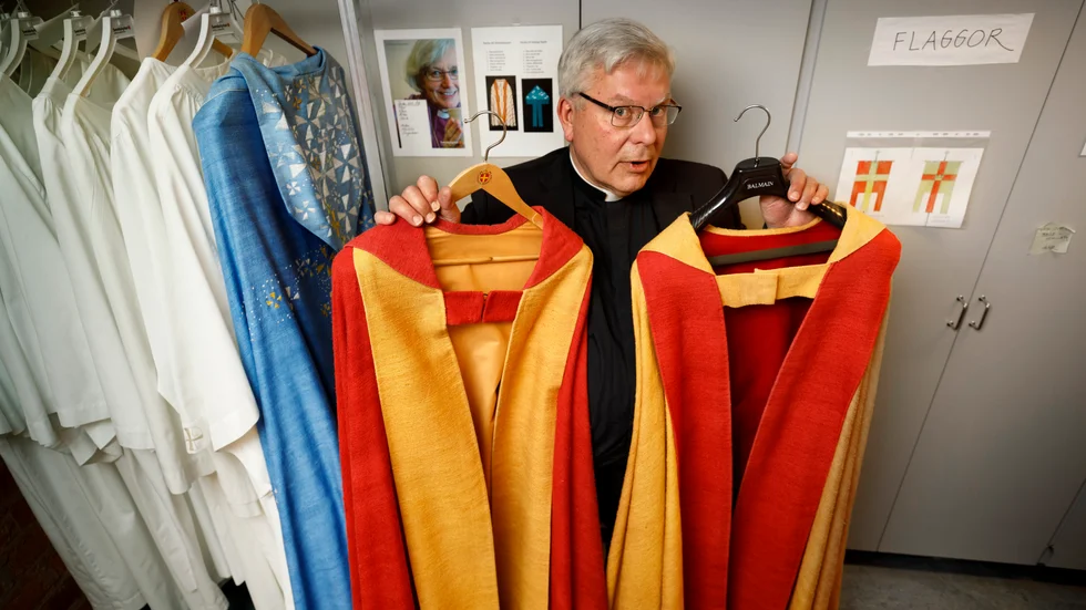 Domkyrkokaplan Lars Åstrand visar två kåpor i domkyrkans färger i Skrudrummet.