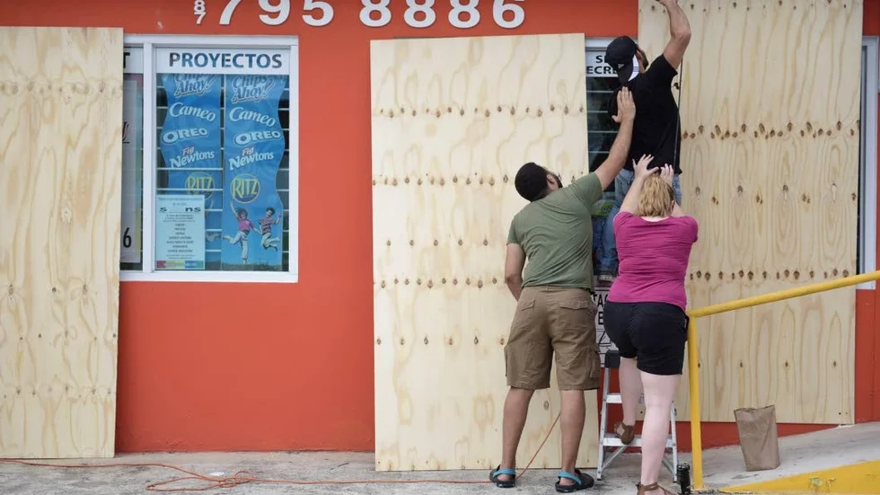 CORRECTS CITY - Cyber School Supply Christopher Rodriguez is supported as he installs wood panels over a storefront window in preparation for Hurricane Irma, in Toa Baja, Puerto Rico, Tuesday, Sept. 5, 2017. Irma grew into a dangerous Category 5 storm, the most powerful seen in the Atlantic in over a decade, and roared toward islands in the northeast Caribbean Tuesday. (AP Photo/Carlos Giusti)