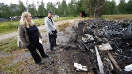 Marlene och Johan Schelin vid resterna av ladan där de förvarade sitt bohag.