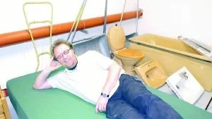 Ulf Larnemark, chef för Hela Människan, pustar ut på en säng. I butiken säljs alltifrån badkar till gosedjur.