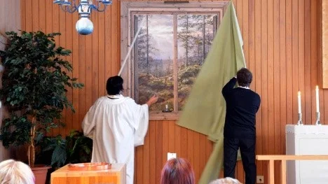 Kyrkoherde Ingrid Holmström Pavval och kyrkvaktmästare Jan Larsson avtäcker Gärdis Lindgrens konstverk.