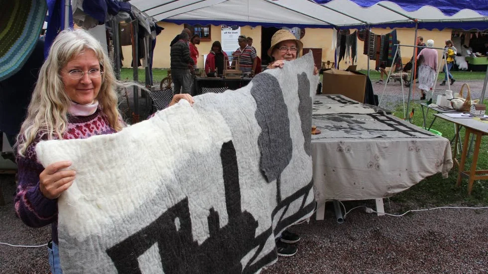 Elisabeth Stjärnfors och Lisa Ristikartovisar upp den tovade bonad som ska placeras i festlokalen i Folkets hus i Hargshamn för att ge en bättre ljusnivå.