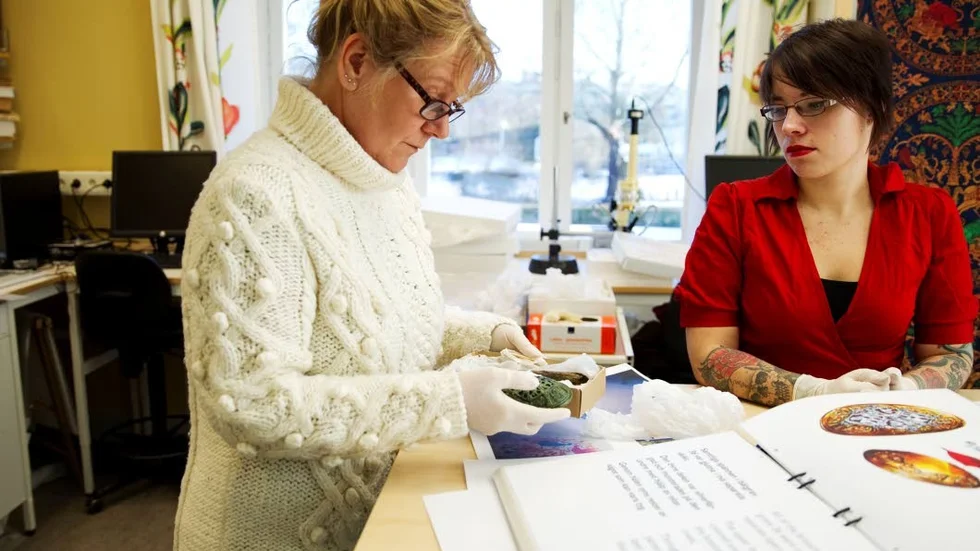 Utifrån detaljerade analyser av de bevarade sidenfragmenten från båtgravarna och jämförelser med kända forntida tygmönster försöker arkeologen Annika Larsson och tecknaren Wera Olsson rekonstruera hur begravningsdräkterna såg ut.  I bakgrunden till höger hänger ett av de rekonstruerade tygerna med mönster och motiv från persisk mytologi.