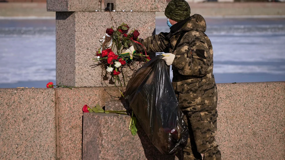 En kommunal arbetare plockar undan blommor som har placerats ut i S:t Petersburg för att högtidlighålla minnet av den döde Aleksej Navalnyj. Bilden togs på måndagen.