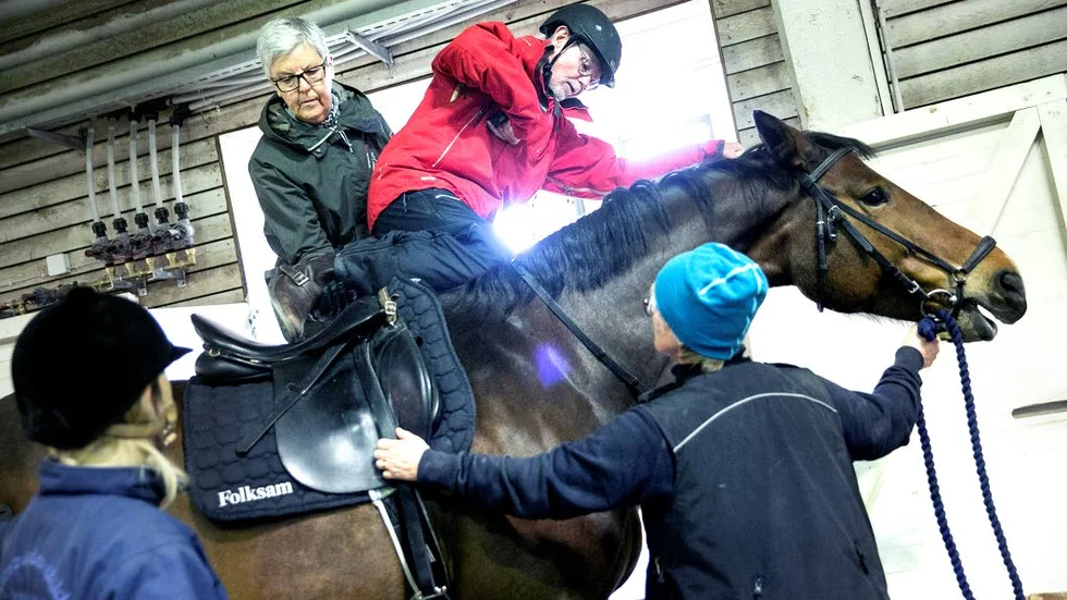 STÄRKANDE. Nils Anundby har åkt hiss till en handikappramp från vilken han kliver på hästen Secret. Inger Anundby hjälper honom att få över det högra benet. Ridningen stärker både motorik och balans.