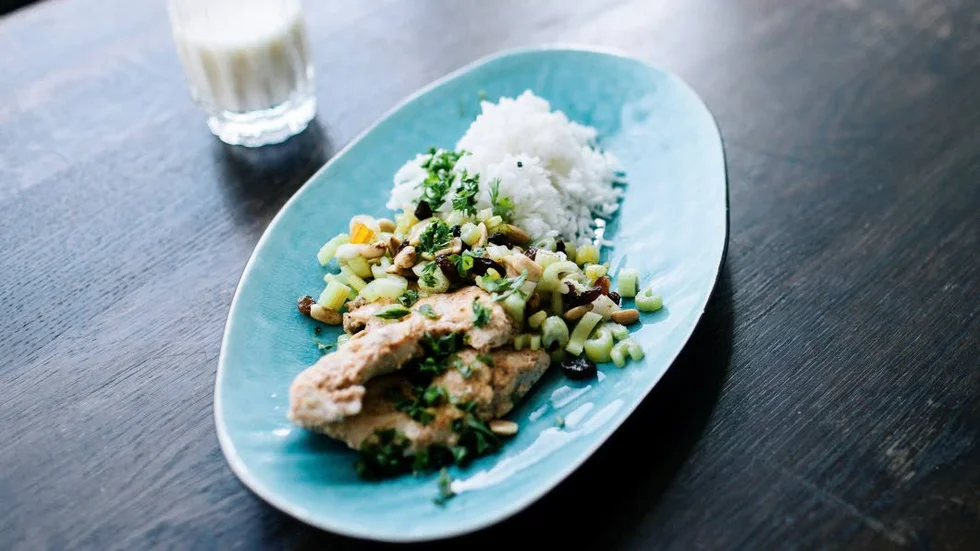 Tandoorikyckling med ris och sallad på selleri, frukt och nötter. Till det serveras ett glas lassi.
