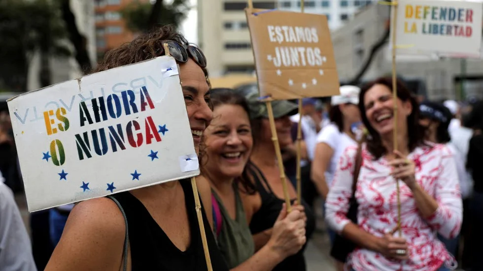 Medlemmar av oppositionen i Venezuela håller skyltar med meddelandet ”Det är nu eller aldrig”.