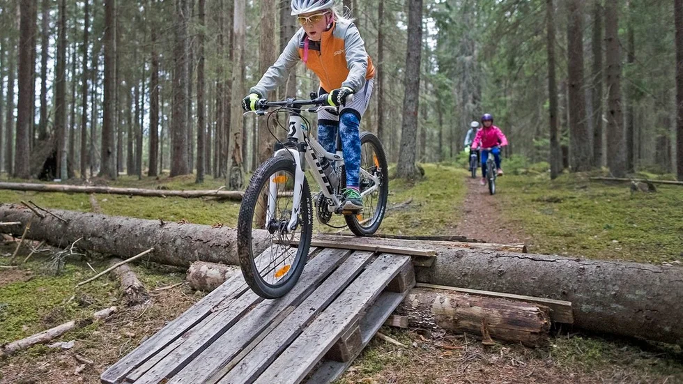 Sofi Norlander far fram på cykeln i skogen vid skjutbanan på åsen.