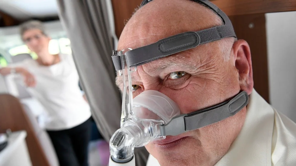 Kent Rickbo med sin CPAP-mask i husbilen i Vellinge. I bakgrunden hustrun Gunilla.