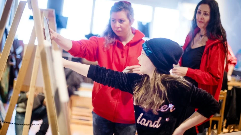 Personalen på The Culture house utmärker sig med röda luvtröjor, till vänster Erika Andersson och till höger Jannica Lund. 11-åriga Miranda Alakoski går på klasser i måleri och dans.