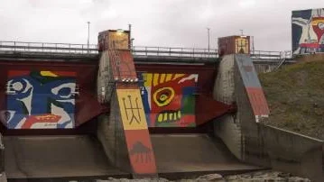 BLANDADE KÄNSLOR. Dammluckorna vid Akkats kraftstation har av Lars Pirak och Bengt Lindström prytts med konstmotiv med samisk anknytning. Monumentalmålningen har väckt blandade känslor, Vattenfalls respektive rennäringens behov har genom åren inte varit konfliktfria. Foto. PÄR DOMEIJ