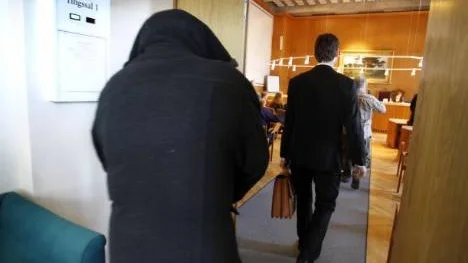 Den åtalade kvinnan på väg in i rättssalen. Åklagaren har åtalat föräldraparet för grov fridskränkning av sina barn, i dag 17 och 19 år gamla.