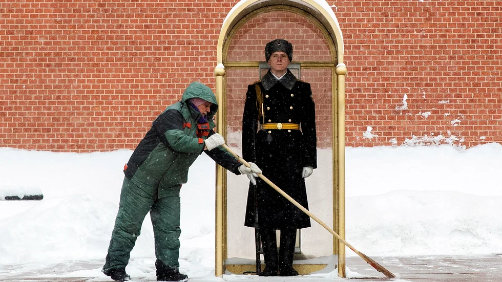 En man sopar bort snö framför en vakt vid Moskvamonumentet Den okände soldatens grav i februari 2021.
