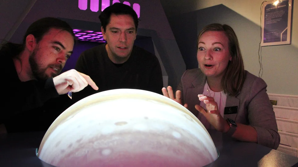 Thomas Clifford, Andreas Anglesjö och Kim Brax i ljuset av planetbordet och Jupiter inför öppningen av utställningen Rymdskeppet.