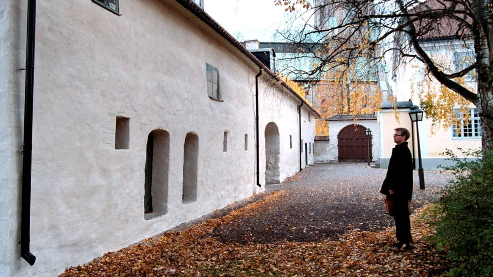 Vid Biskopsgården 1999. Den här vita längan vid Biskopsgården har inte varit någon del i ett kloster även om arkeologerna i många år gärna ville tro det. Göran Tagesson grävde invid Biskopsgårdens gavel -- men hittade ingenting som kunde sättas i samband med ett kloster.