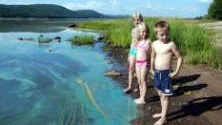 Hanna Ledin, 9, Agnes Johansson, 7, och Melvin Björnström, 6, vill gärna hoppa i vattnet men vet inte riktigt om de borde låta bli. Enligt Holger Hansson-Palo på miljö- och byggnadsnämnden avråder kommunen från bad så länge skylten sitter uppe. FOTO: Anette McMurry