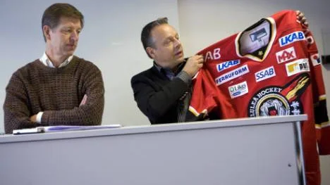 Michel Östlund, Spädbarnsfonden, och Peter Jidström, klubbdirektör i Luleå Hockey, visar upp den ditsydda symbolen Solvända på matchtröjan.