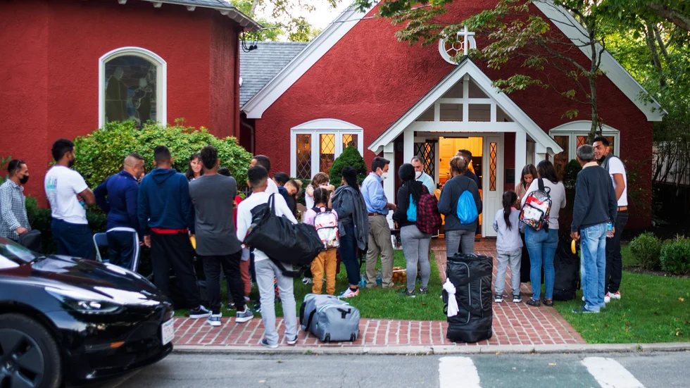 Migranter som flugits från Florida samlas utanför en kyrka på semesterön Martha's Vineyard.
