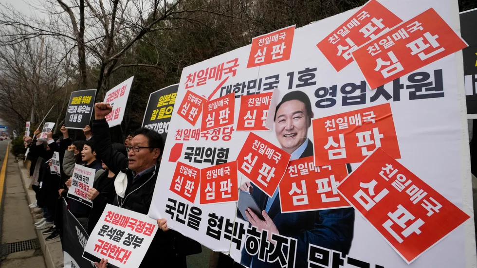 Sydkoreas president Yoon Suk-Yeol ska till Japan. Här syns han på ett plakat vid en av veckans protestaktioner mot honom.