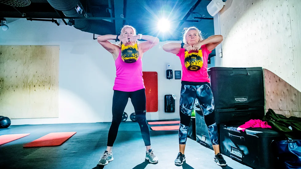 Kicki och Monica lyfter sina kettlebells med van hand.
