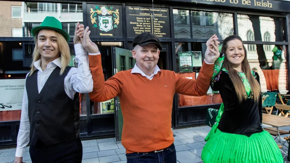 Fancy a dance? Neil Doherty bjuds upp av Aidan Gärdlund (vänster) och Linnéa Skoglund (höger) från  Saoirse Irish Dance Company, ska uppträda utanför puben på fredag.