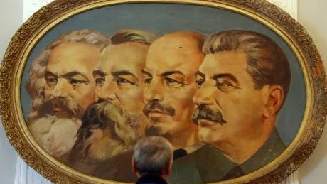 En man betraktar en tavla föreställande fyra av kommunismens förgrundsgestalter. Från vänster: Karl Marx, Friedrich Engels, Vladimir Lenin och Josef Stalin. Alla är döda sedan länge. Men de har till 80 procent fått igenom sin politik. I vart fall i Sverige, det skriver Stig-Björn Ljunggren i denna söndags betraktelse.
