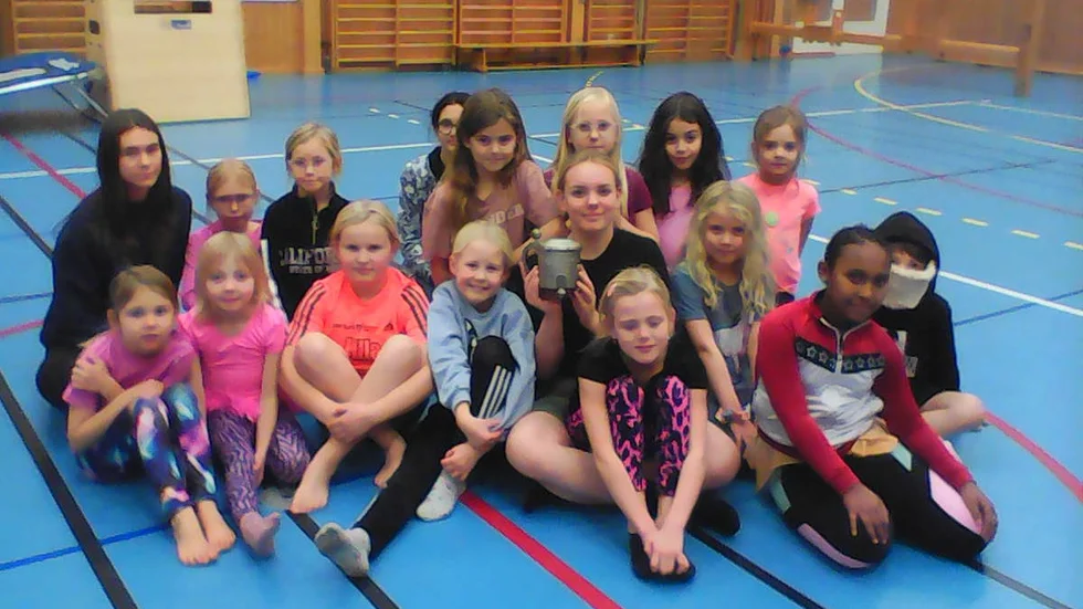 Eline Johansson, hållandes Svebecks kamratpris, omgiven av några av gymnasterna i Motala gymnastikförening