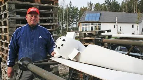 Jonny Warg vid det ännu inte uppsatta vindkraftverket. I bakgrunden det nybyggda energisnåla huset med solvärmepaneler på taket.