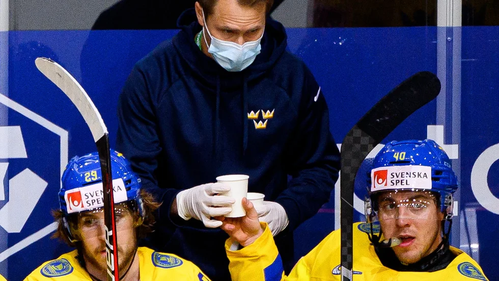 Markus Hast ger Andreas Wingerli lite dryck i båset i Tre Kronors segermatch mot Schweiz. Till vänster Mario Kempe.