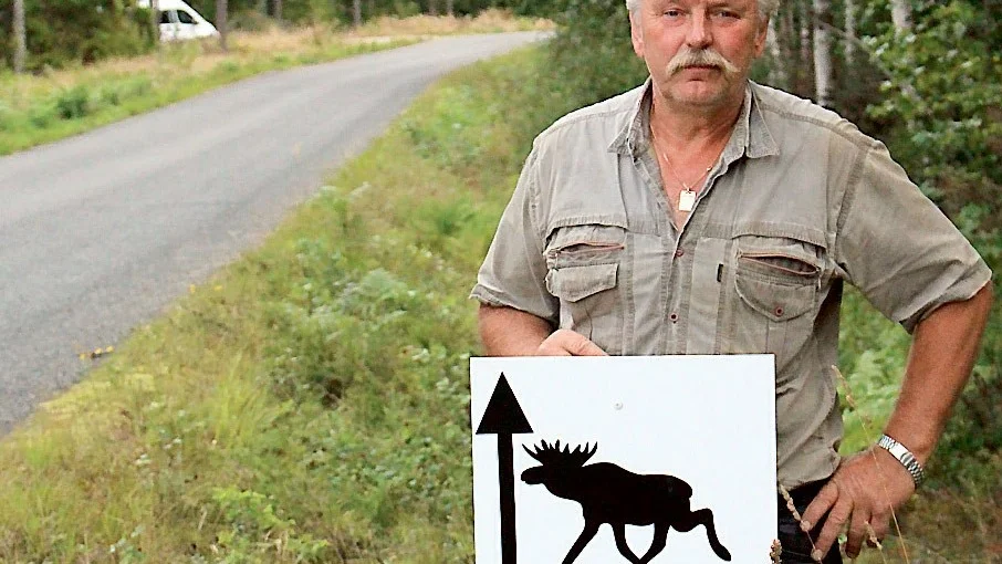 Kjell Svensson vid en av sina egna skyltar som egentligen är olagliga. Men han menar att de behövs för att besökarna ska hitta till älgparken.