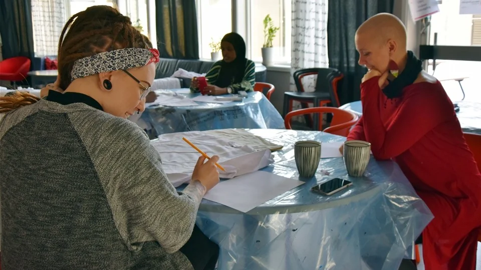 Närmast kameran sitter Angelica Allén och Lena Johansson. Längre in i lokalen sitter Nasteha Hossein. Alla tre sitter och inväntar inspirationen inför tryckeriet